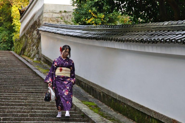 A woman wearing a traditional outfit in a neighborhood in Kyoto