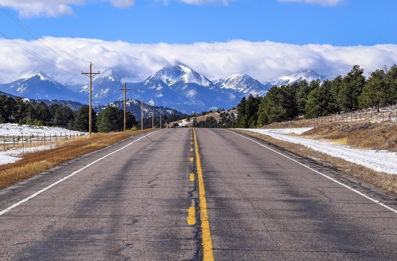 road in colorado leading to snowy mountains