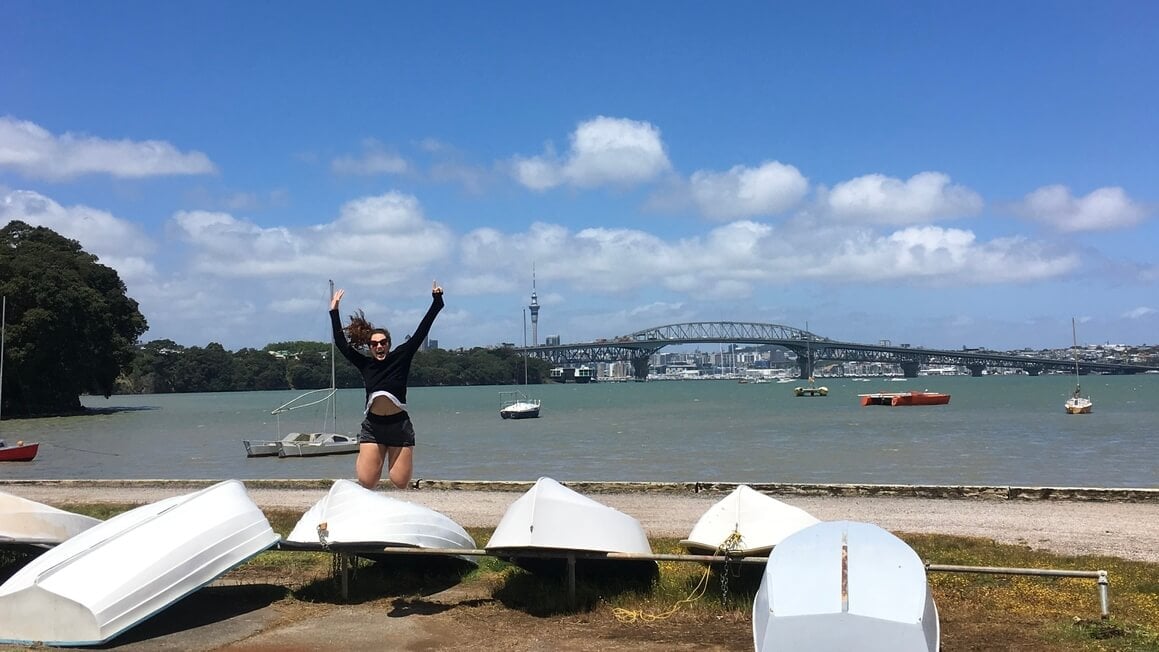 dani jumping off boats at the beach on the north shore of auckland, new zealand with sky tower in the background