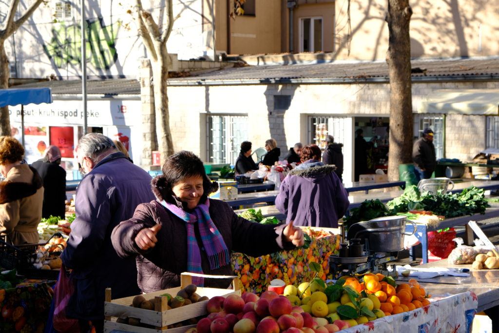 Market vendor smiling over her citrus for sale, sunny winter morning in croatia