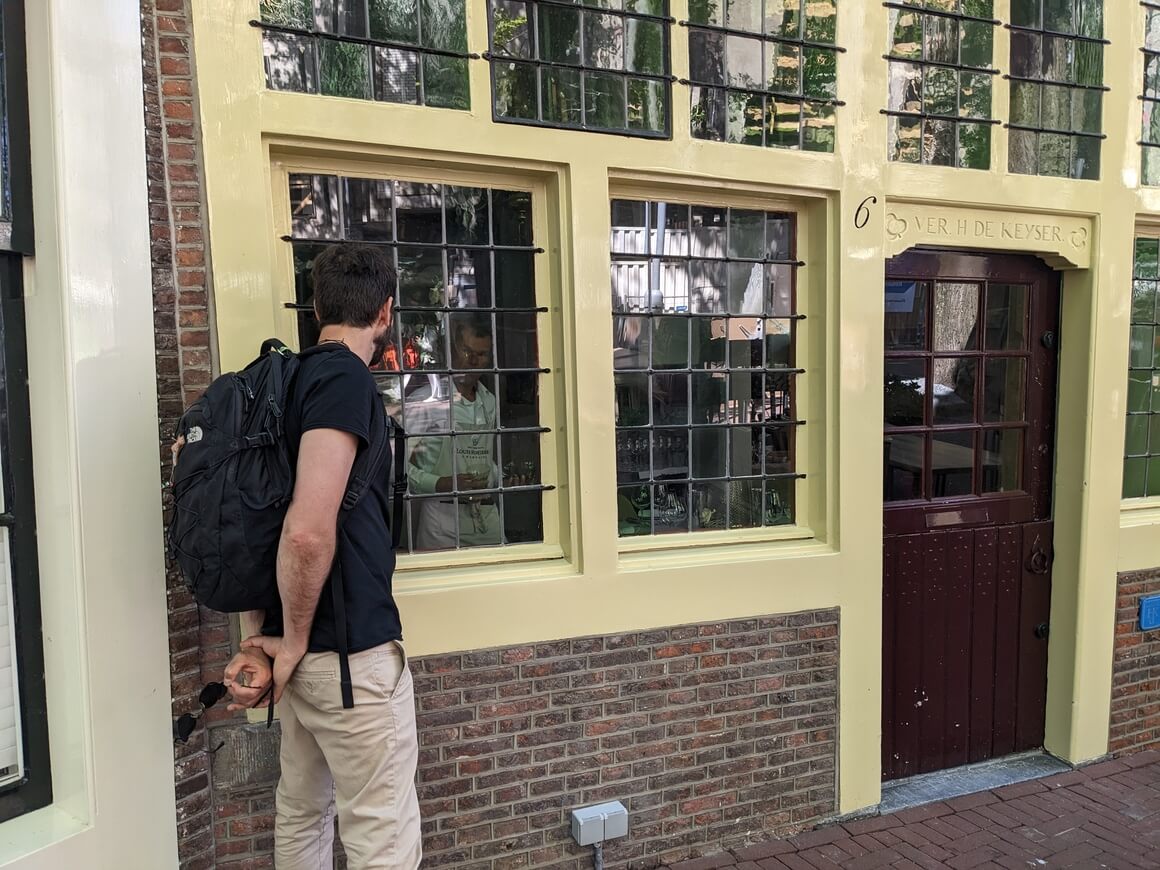 Seba looking inside an old shop window at a baker in Amsterdam