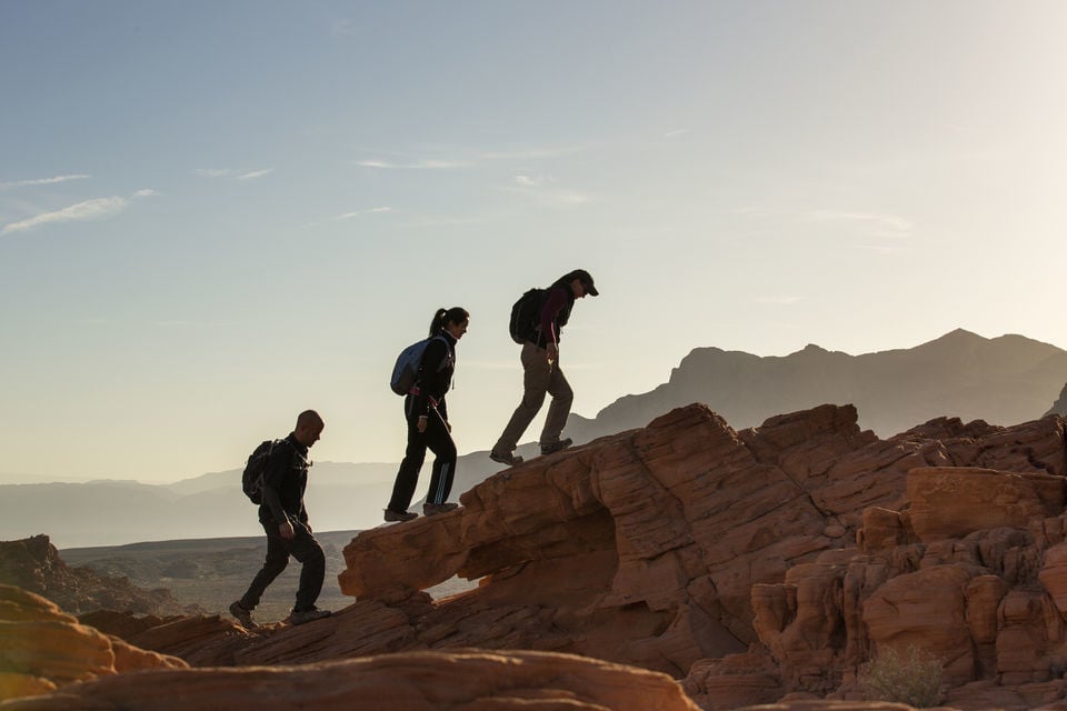 three adventurers scaling a rugged peak