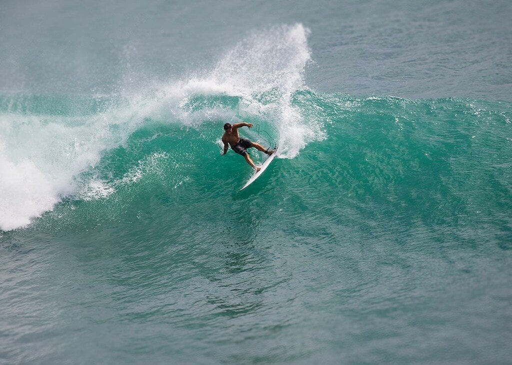 Person riding surfboard on teal-colored waves