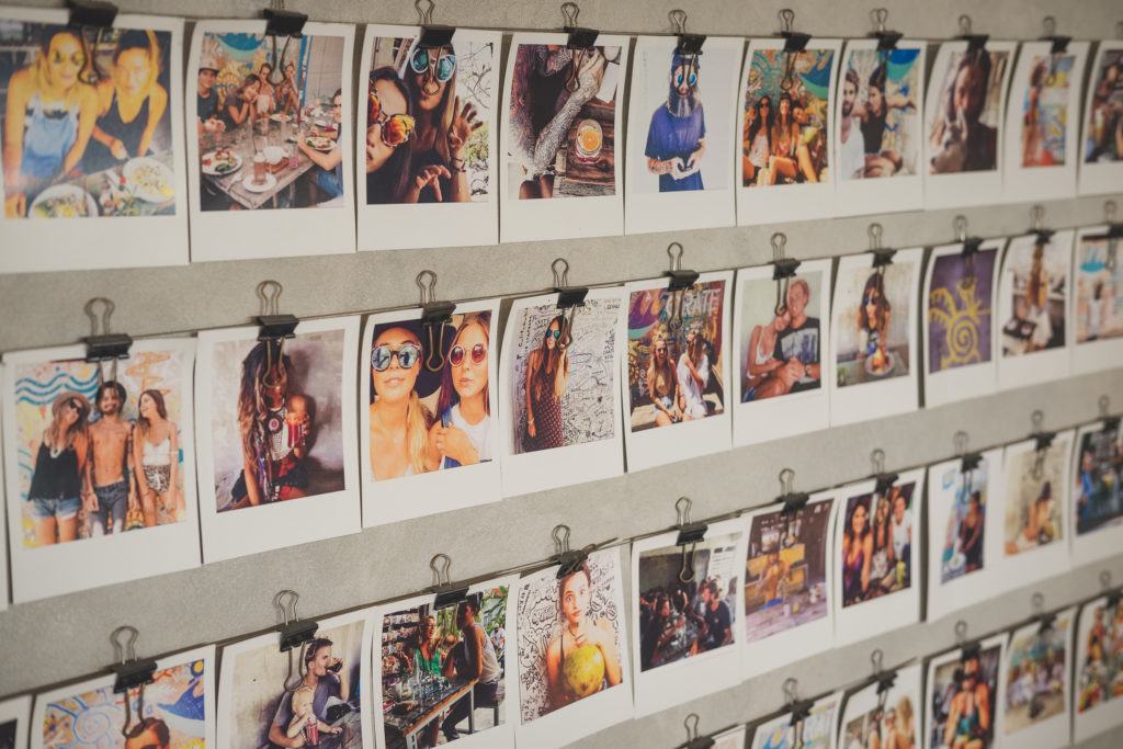 dozens of polaroid pictures of travelers clipped to a wall in canggu bali