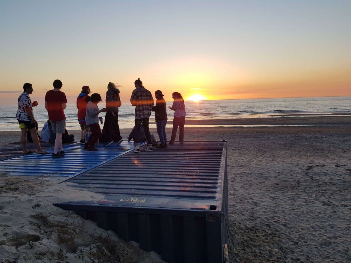 Silhouette of a group of people stood on a container on the beach at sunset in The Netherlands