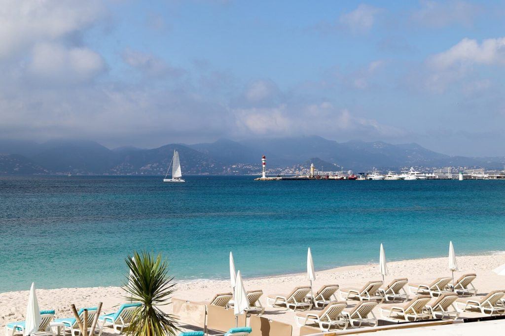 Beach in Monaco with sun beds white sand and azure blue water in front