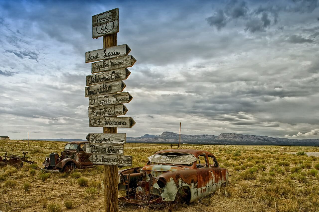 route 66 sign with rusted cars - the quintessential american road trip