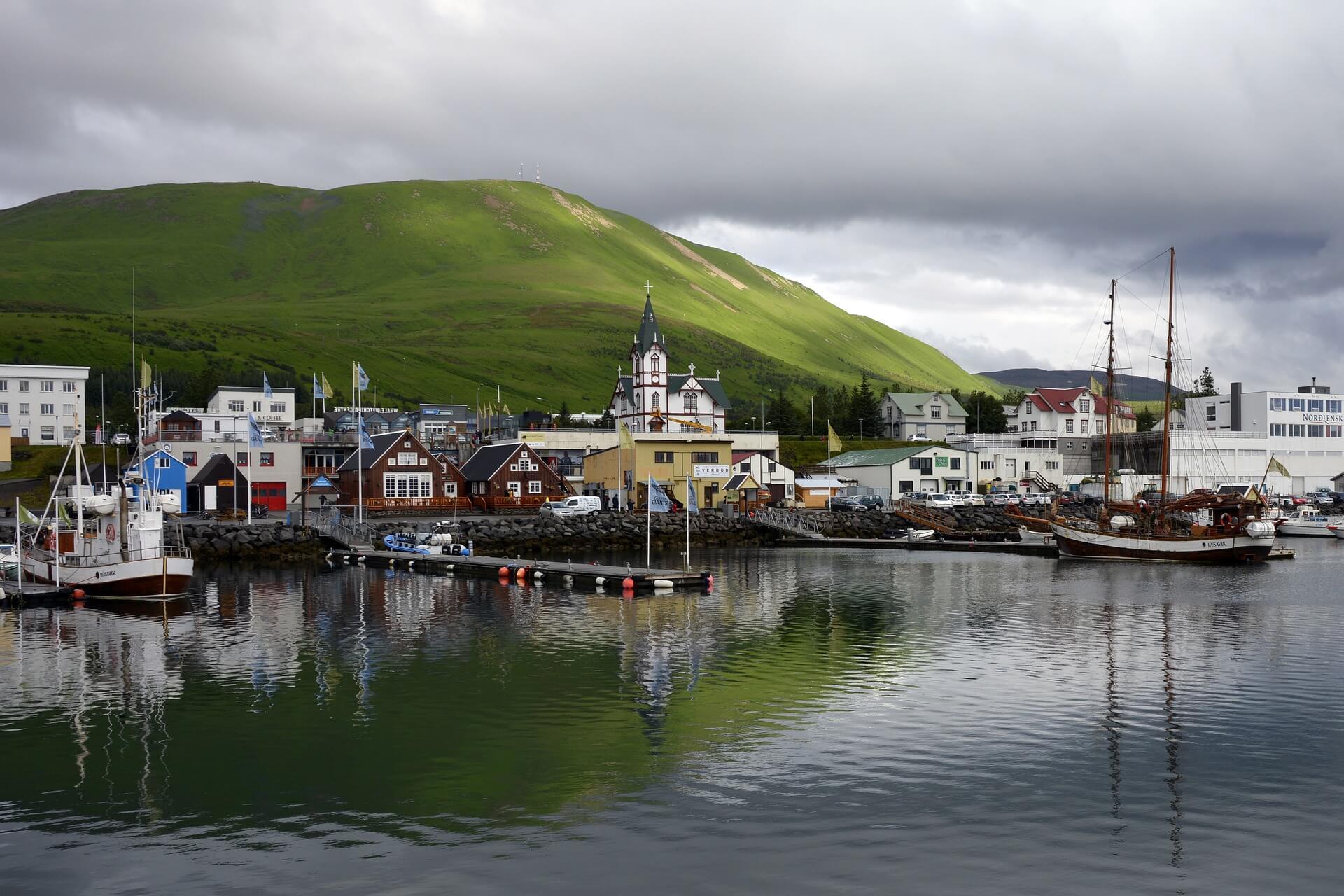Husavik port with a big green hill and rain clouds. Great for families!