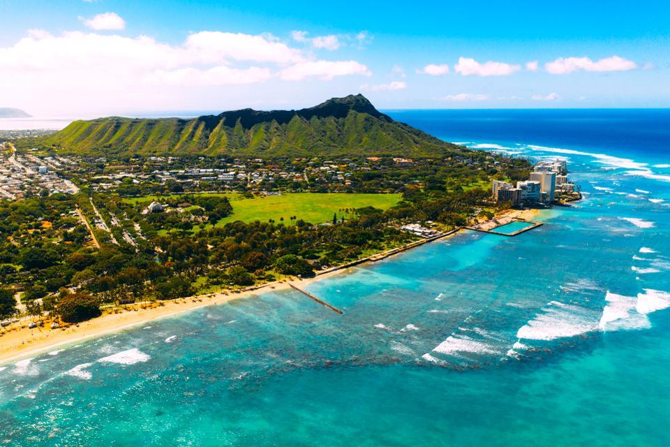 view of the turquoise ocean and green mountains of hawaii from above