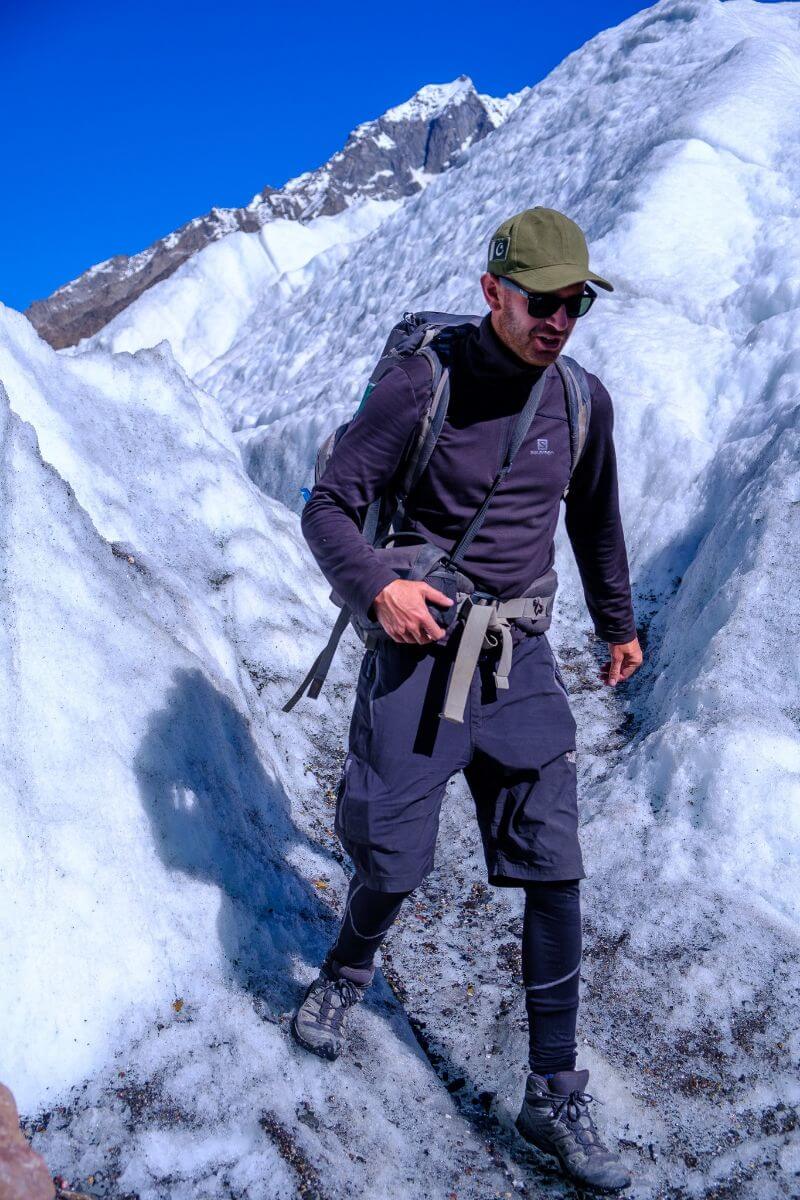 A person high in the mountains in Pakistan wearing boots hiking and climbing