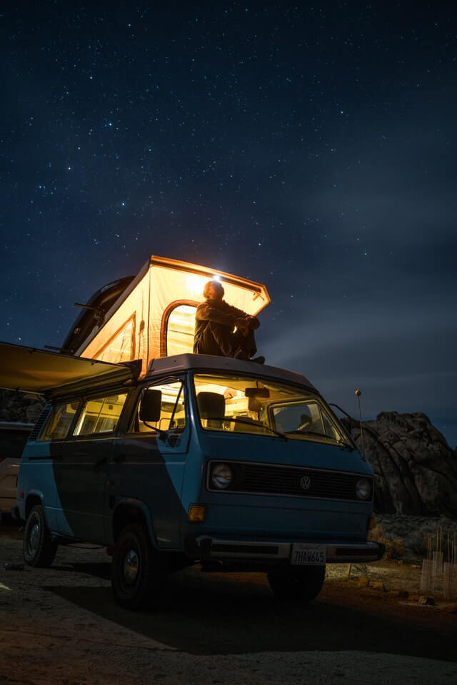 A man enjoys the stars from his van after planning an RV road trip