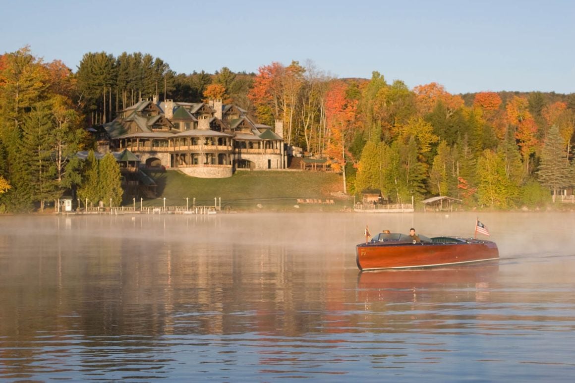 Boat on the water with Lake Placid Lodge in the background with autumnal trees, Lake Placid