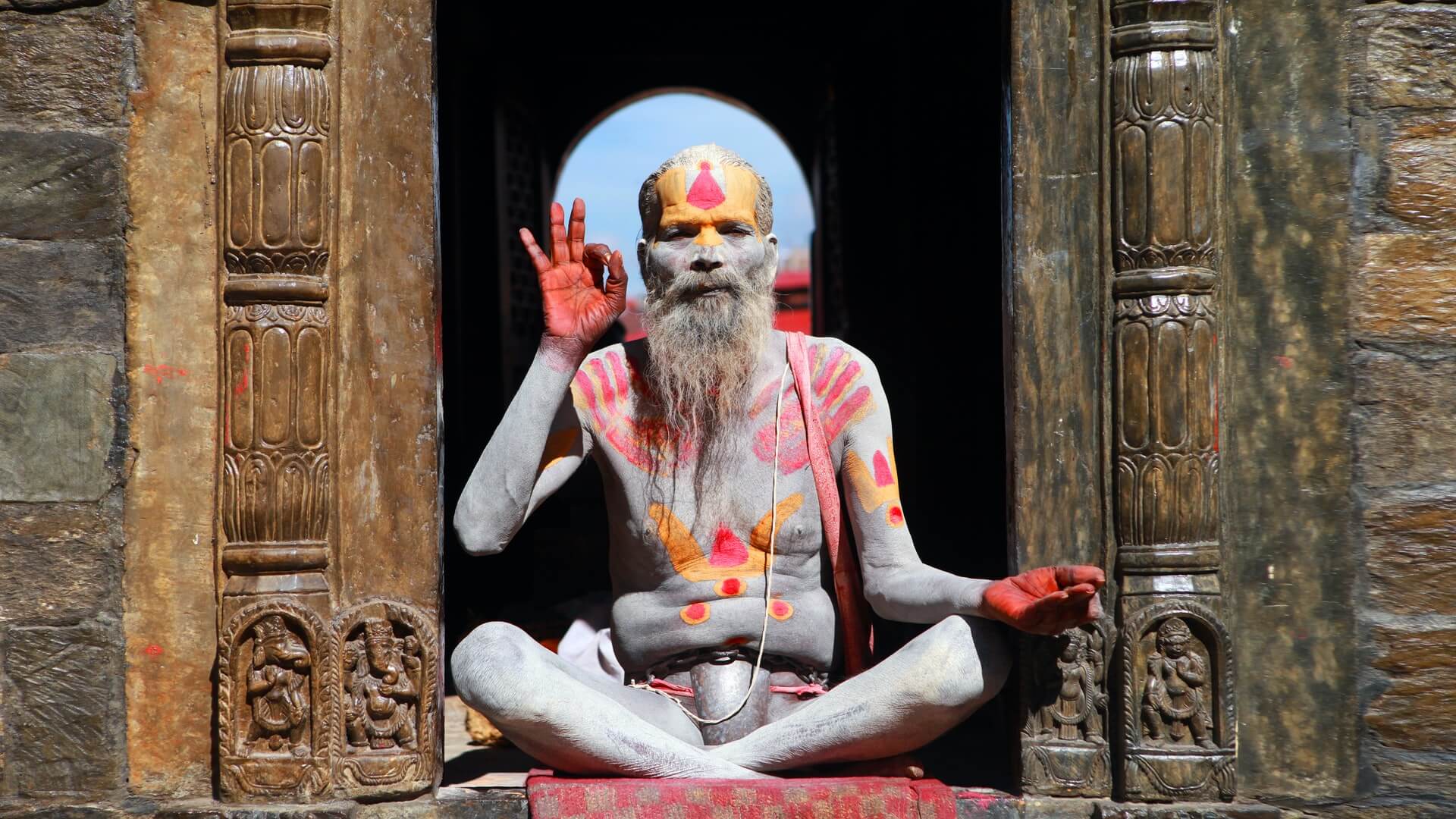 A sadhu in India giving the ok symbol over a well executed drug tourism guide