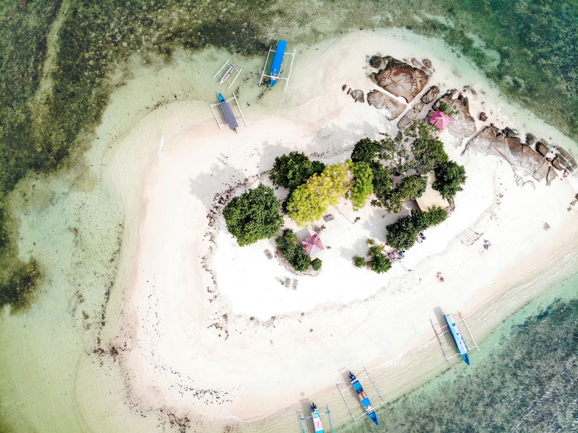 Sky view of Gili Islands with boats lining on the coastline and lush trees