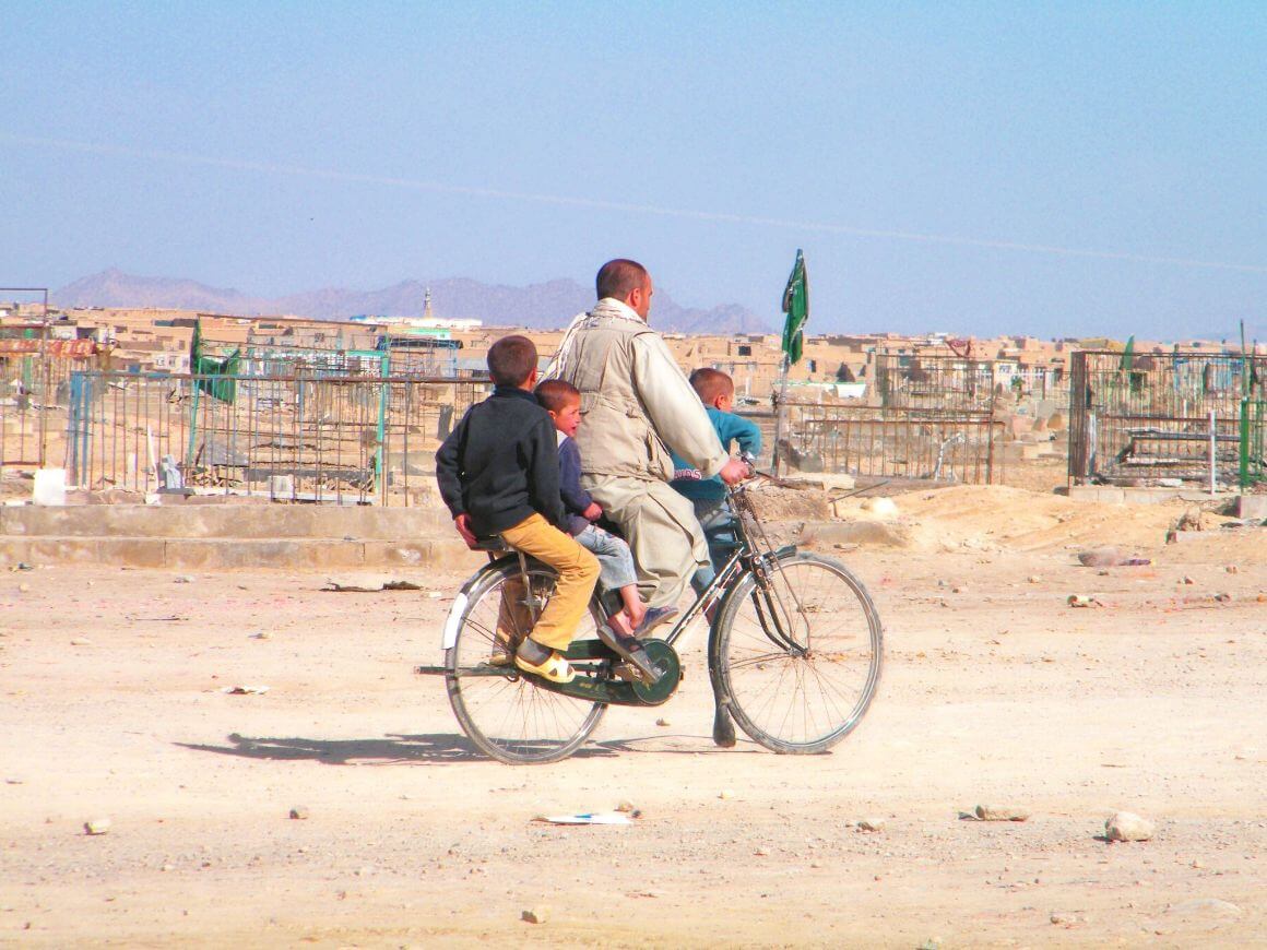 A father and three kids all ride a bicycle together in Afghanistan.