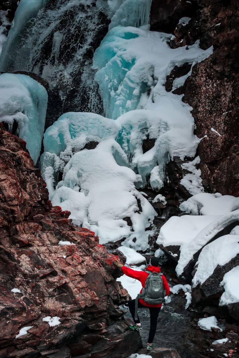 A trekker in Afghanistan stands underneath an ice drift in Panjshir.