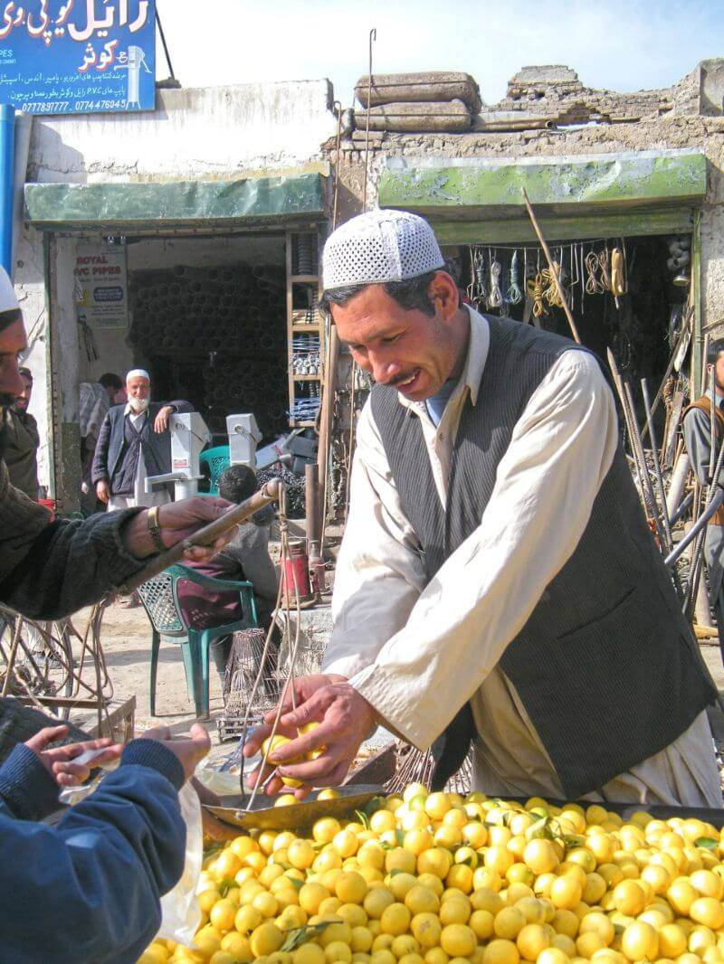 An Afgahni man weighs lemons.