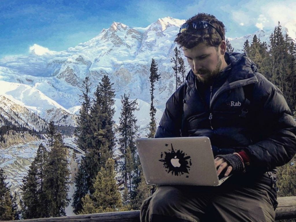 will hatton working on his laptop computer with mountain backdrop