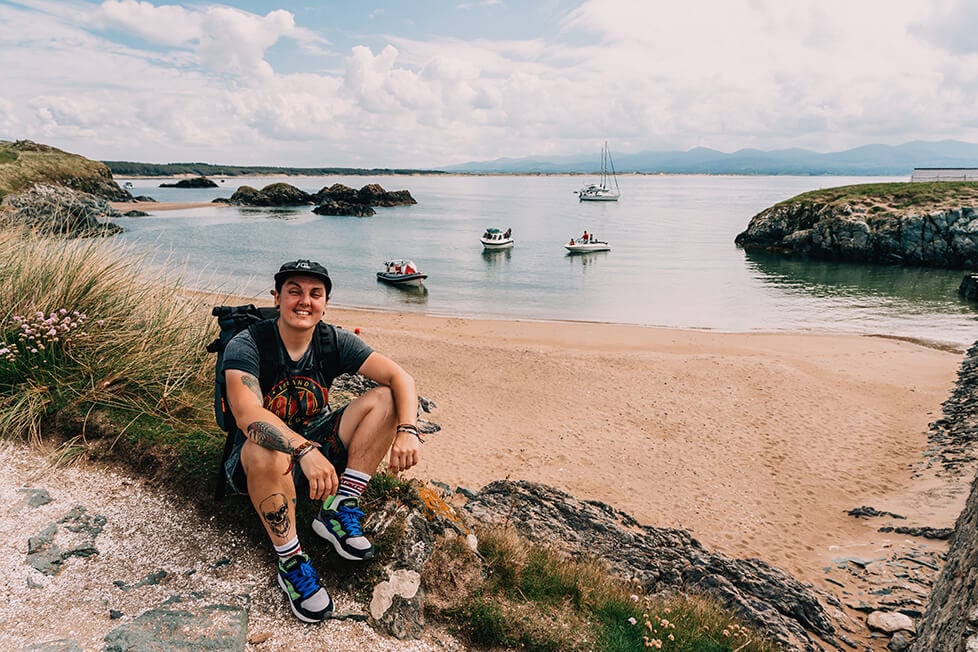 A person sat by the beach in the UK with boats in the background. tbbteam, Wales, United Kingdom