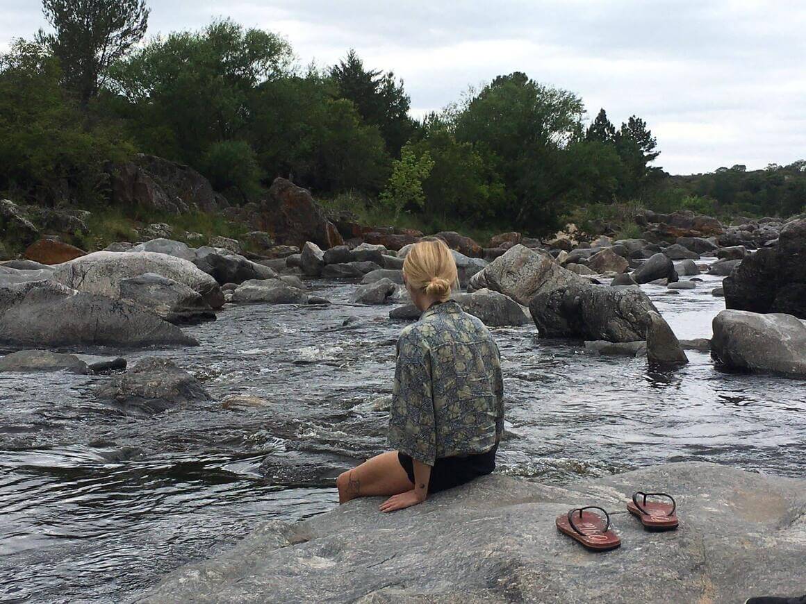 Woman sat by the river in South America with her flip flops off