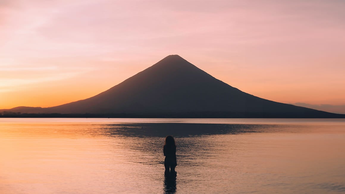 girl in lake watching the sunset at ometepe, nicaragua