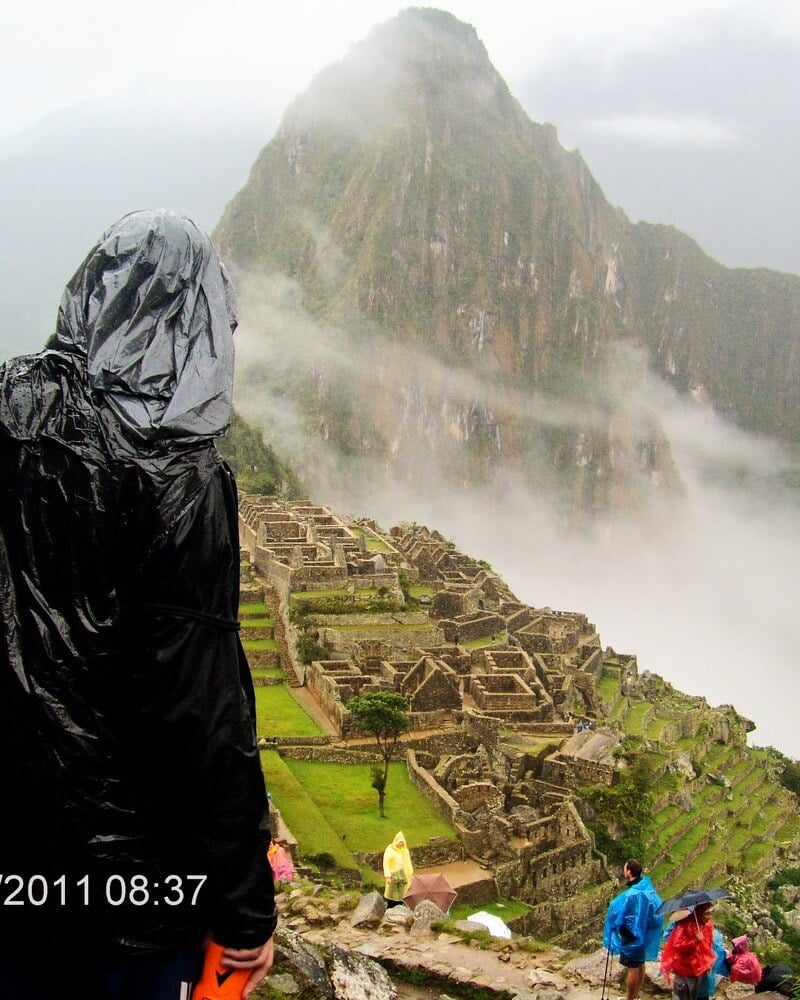Backpacker looking at the old city of Machu Picchu on a rainy day.