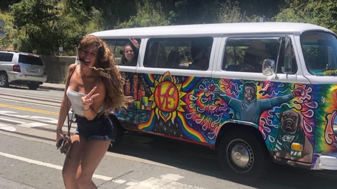 A girl smiling in front of a hippie van in California United States of America.