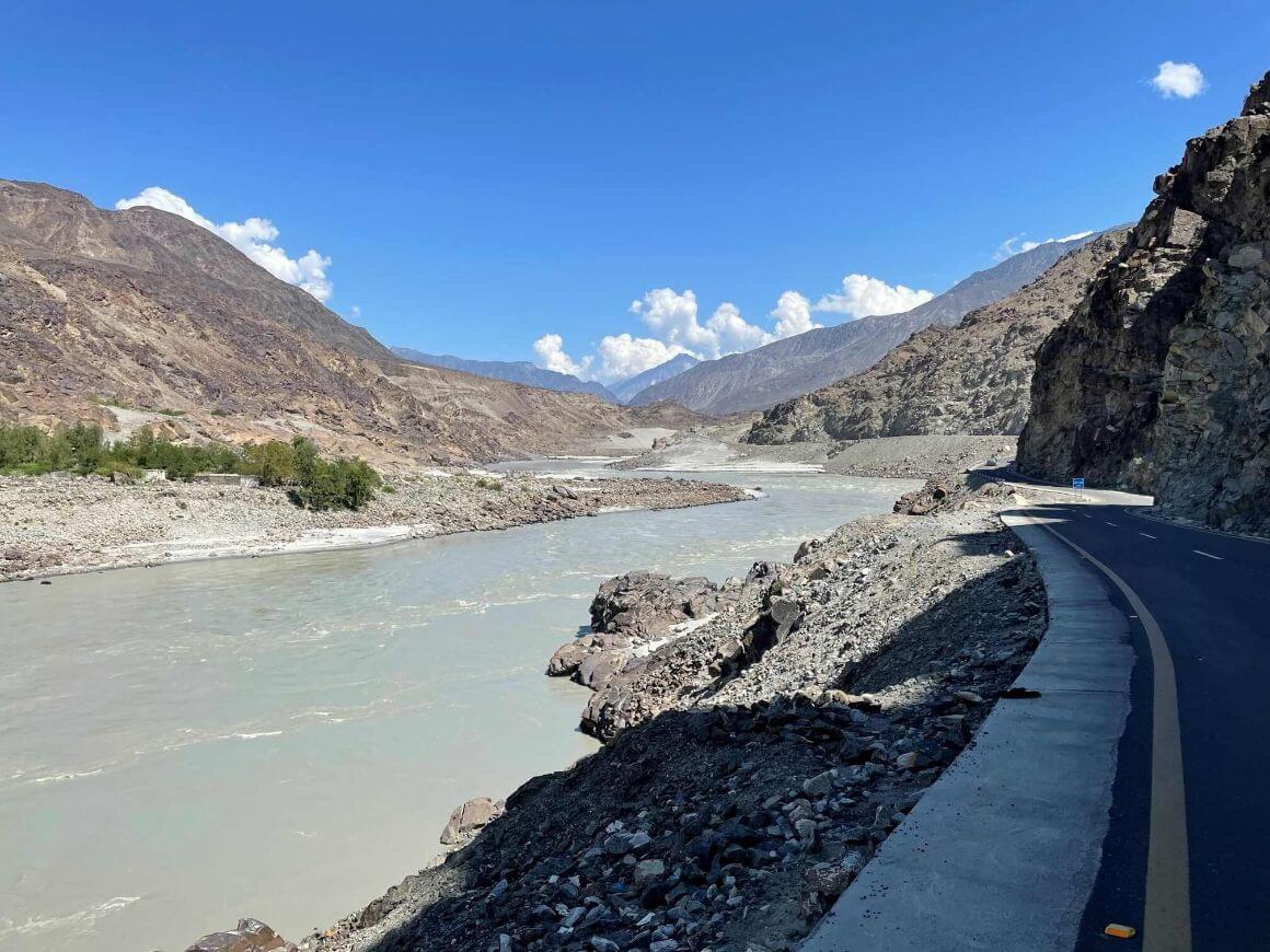 a grey river flowing through a dry rocky section of pakistan's karakoram highway