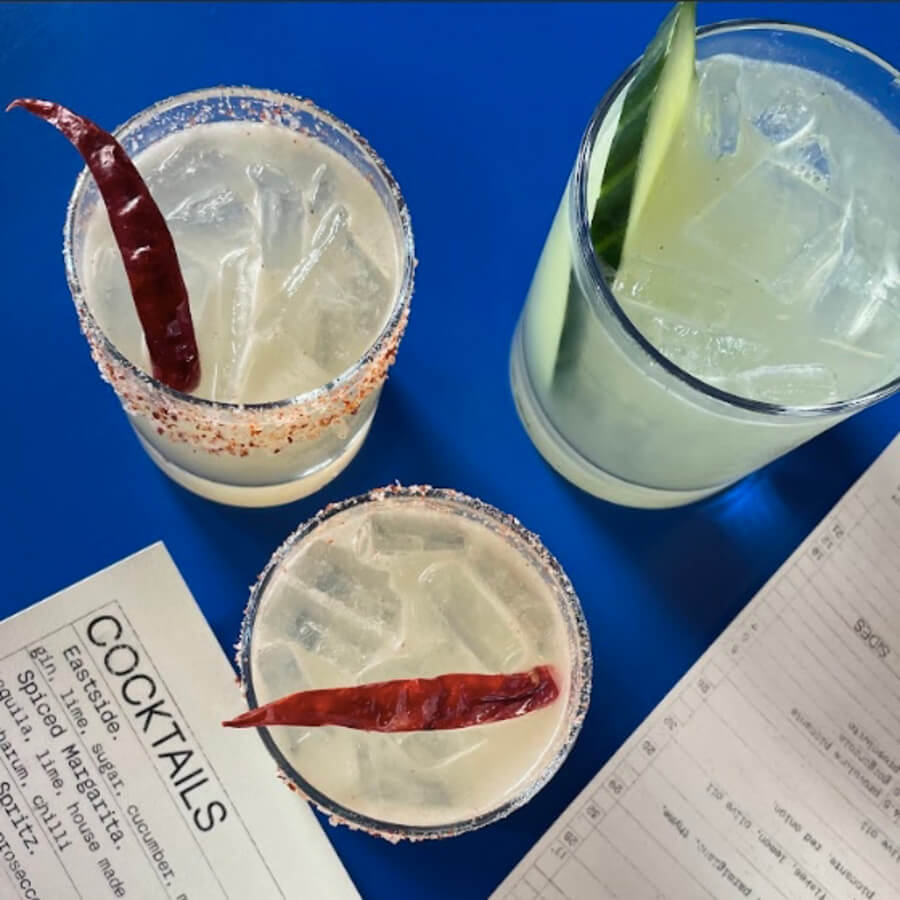 2 spicy margaritas and a cucumber cocktail on a bright blue background