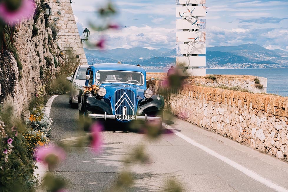 A classic car driving down the coast in Nice, France.