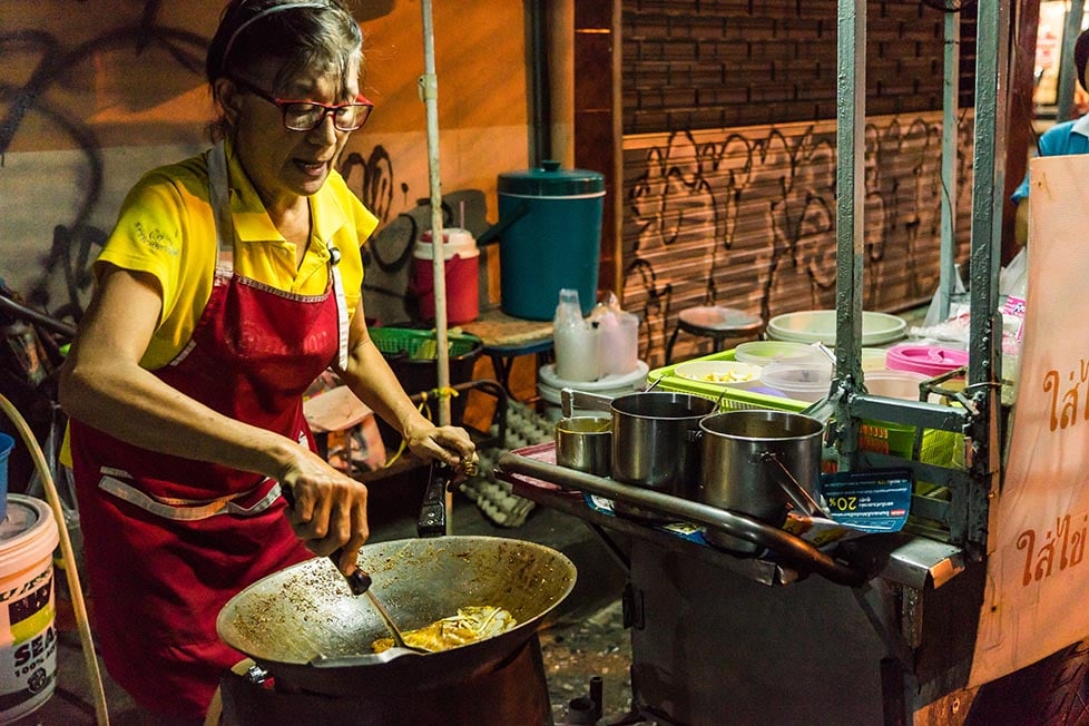 A woman cooking Pad Thai on the street in Bangkok.