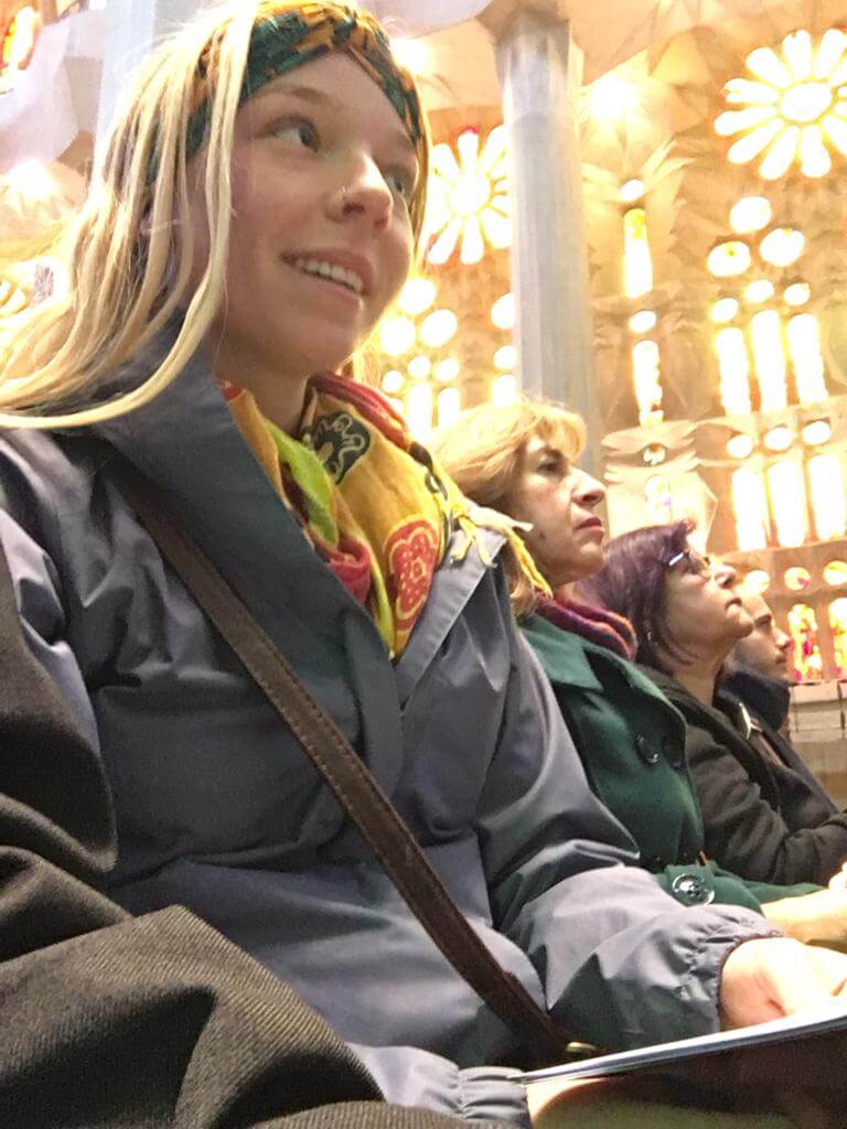 Laura sat in Sagrada Familia Cathedral in Barcelona wearing a coat and scarf