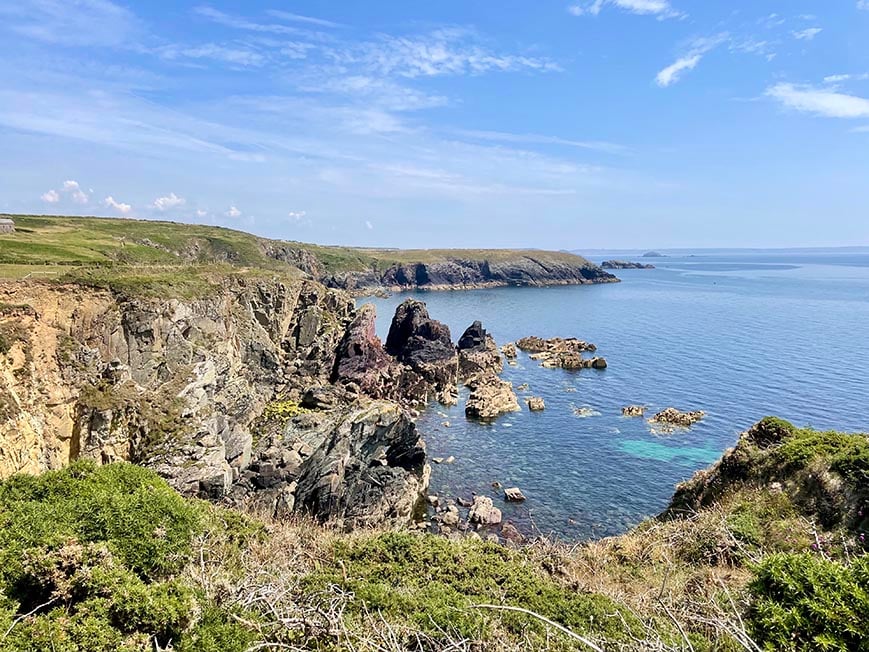 Rugged coastline and cliffs with clear blue water below and a clear blue sky above.