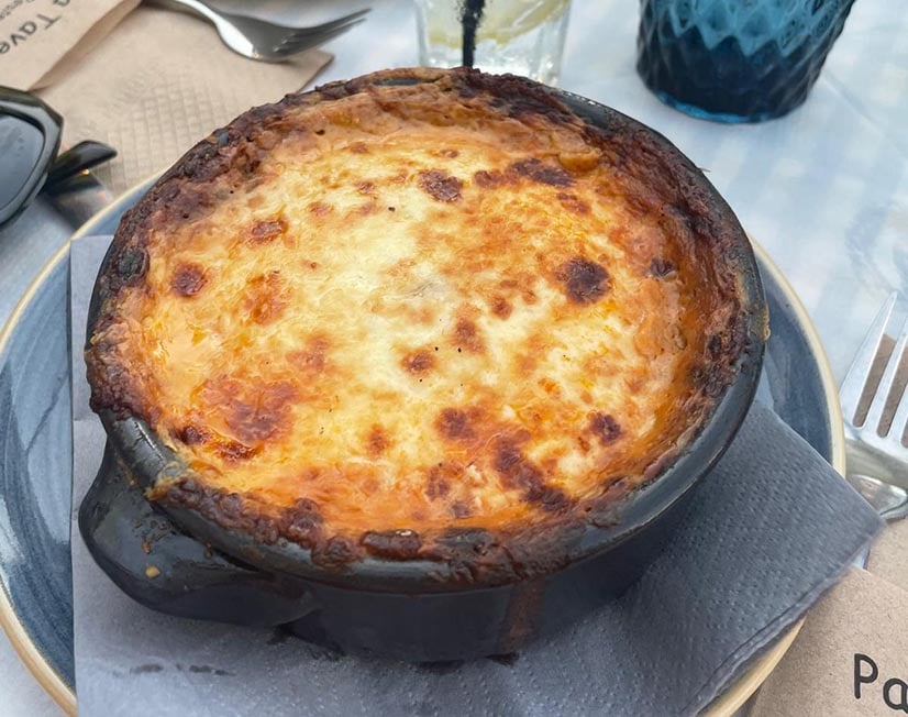 a casserole Greek dish with a brown crust sits on a blue plate