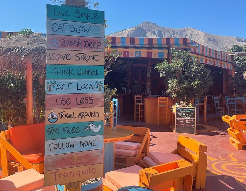 A colorful sign with inspirational messages in front of a restaurant in Santorini, Greece.