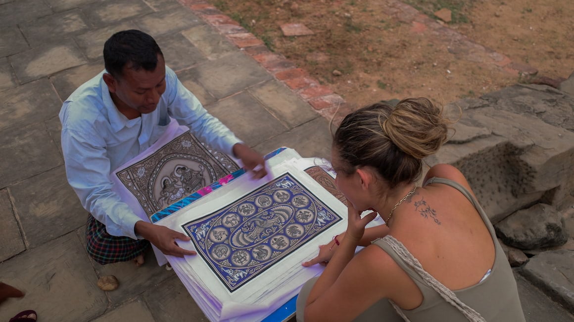 a girl pointing at a art piece a local artist panted in a small village in myanmar