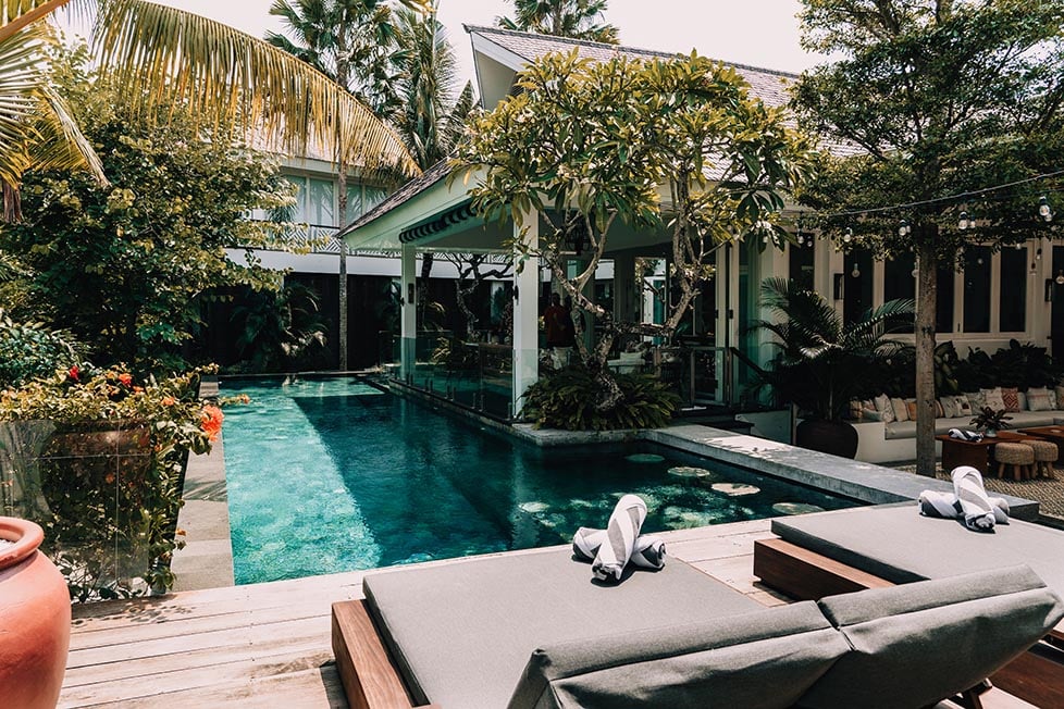 A Canggu villa with a swimming pool and a lounge area surrounded by lush greenery