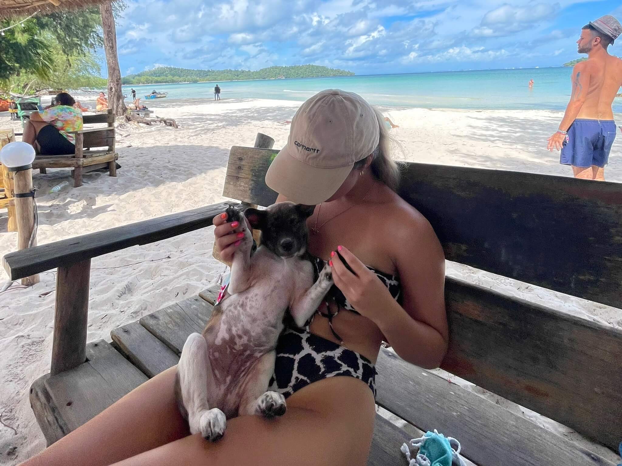 a girl playing with a puppy on a beach in koh rong