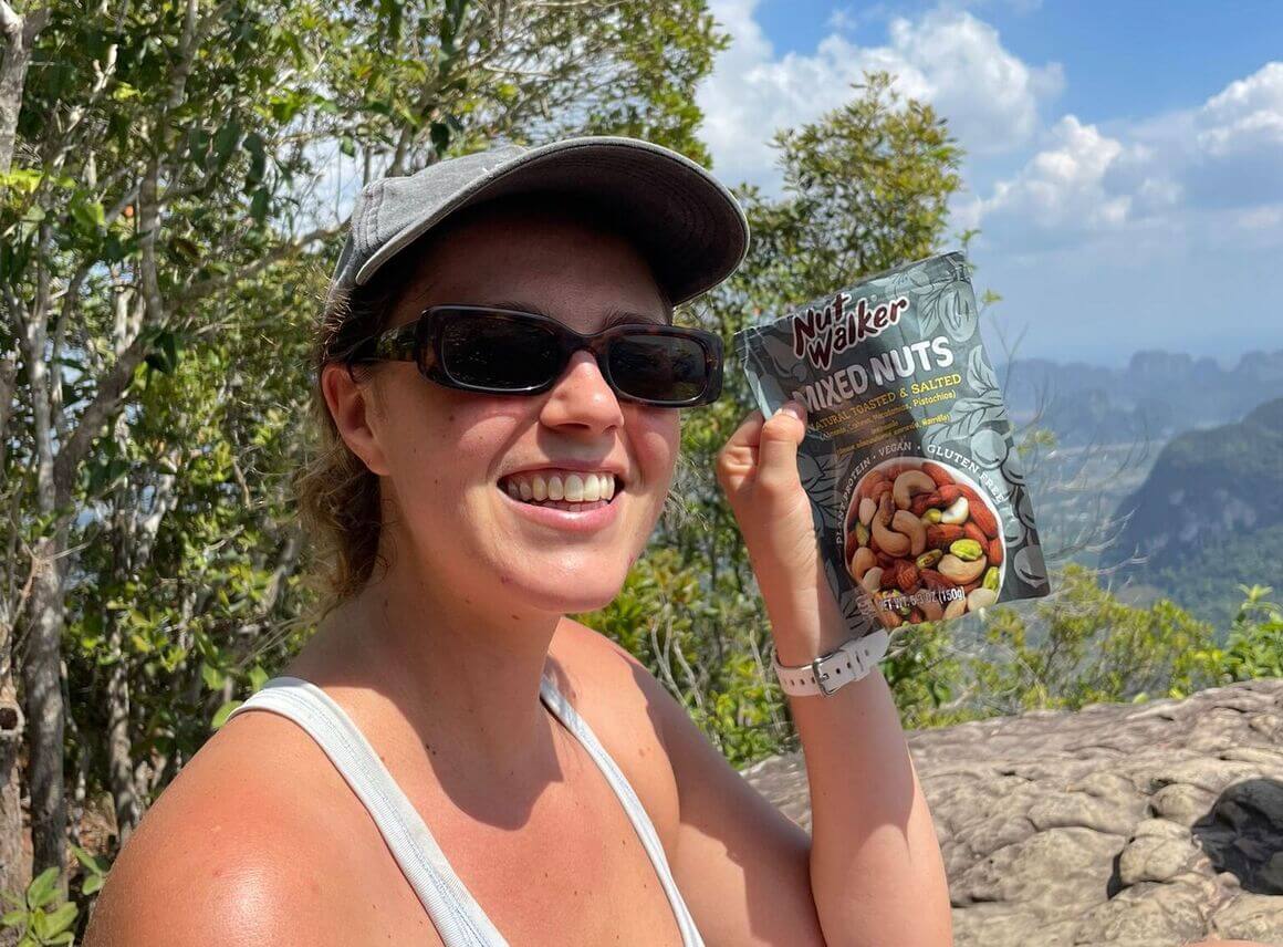 Dani pauses on the trail, snack in hand, surrounded by lush greenery.