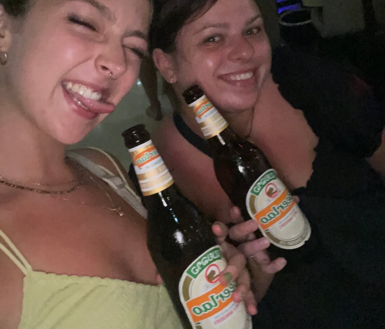 two people smiling and posing with bottles of beer lao