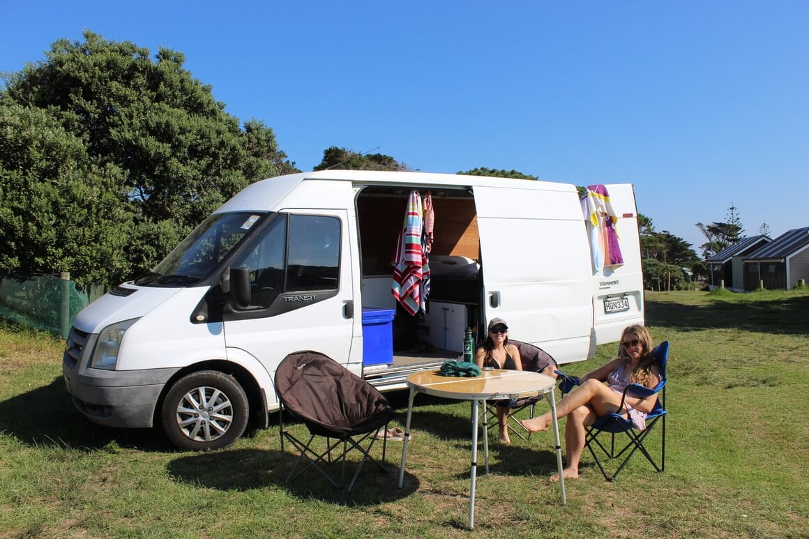 two friends sitting outside a campervan in new zealand