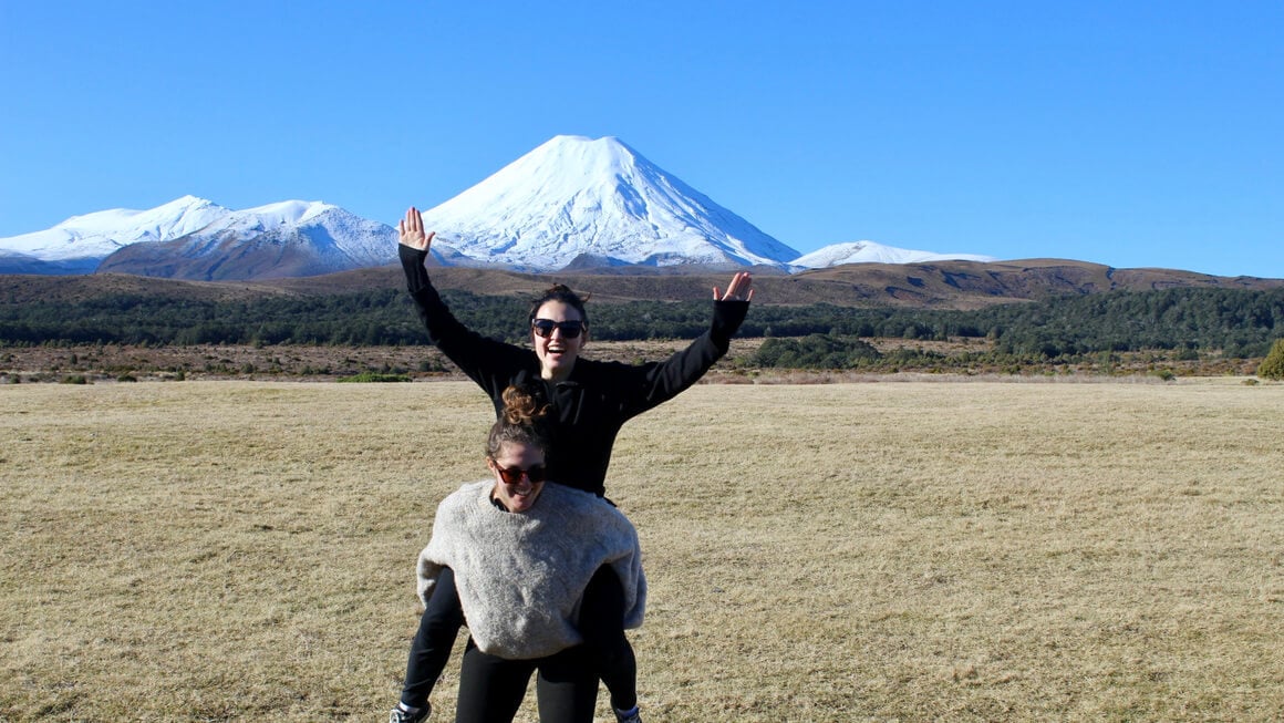 dani and friend at tongariro national park near taupo in new zealand, with snow topped mountains in the distance