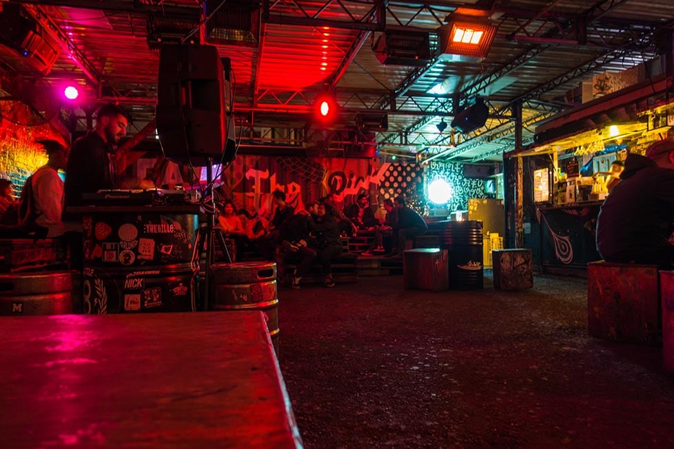 A junk yard bar lit up at night with a DJ playing in Melbourne, Victoria, Australia