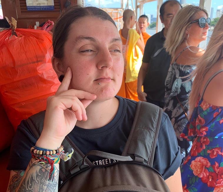 Nic on a canal boat in Bangkok with some monks behind them