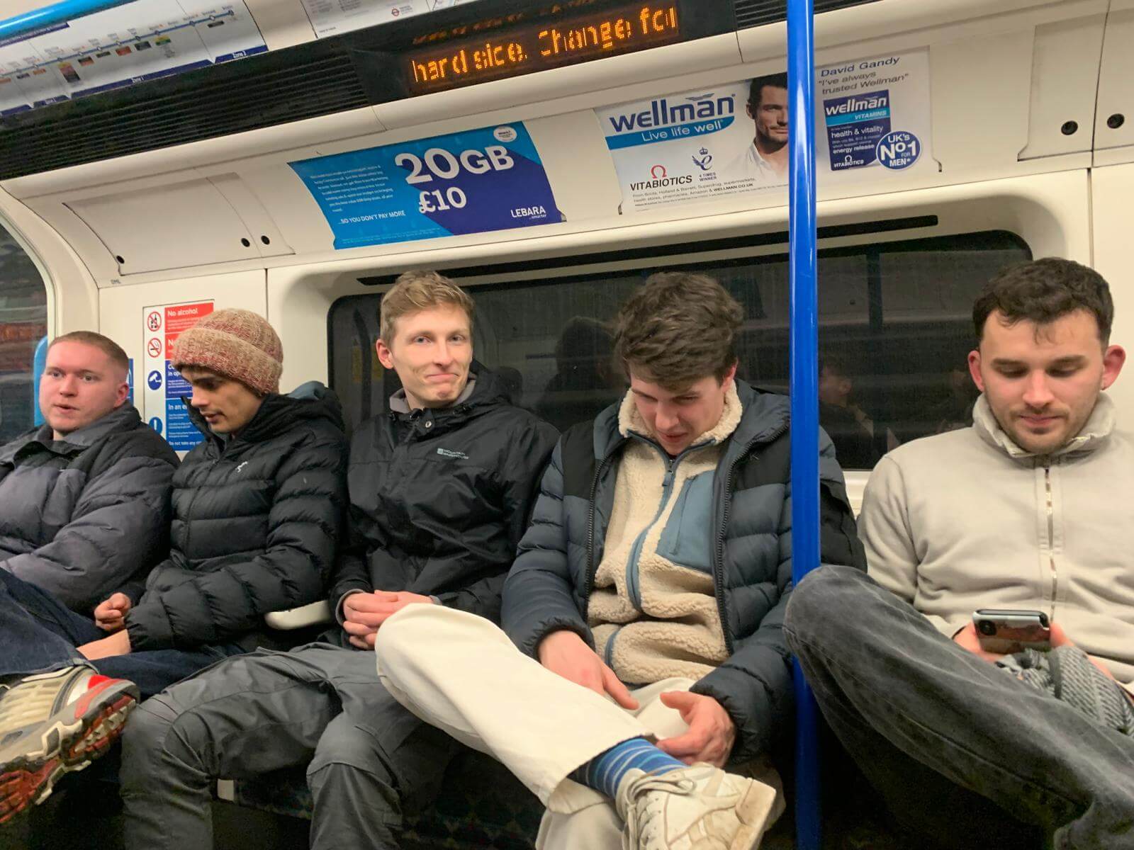 five men sat close together on an Underground train in London