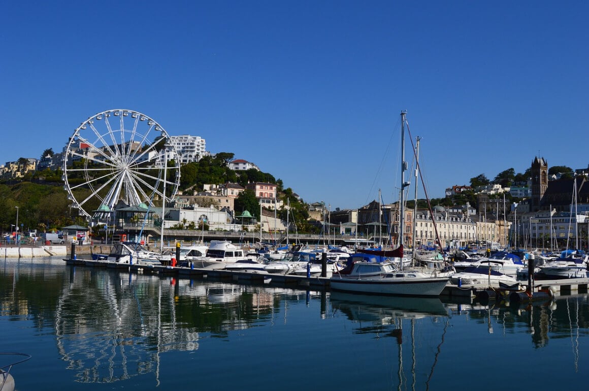 A view of Torquay's port harbor with a Ferris wheel and boats floating on the water.