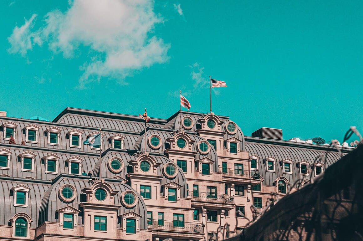 brown and white concrete building under blue skylight during daytime with american flags hanging in dupont, washington dc