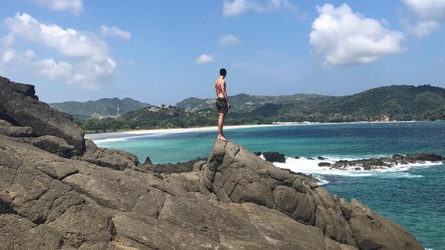 Man on rocks in Indonesia looking out to sea