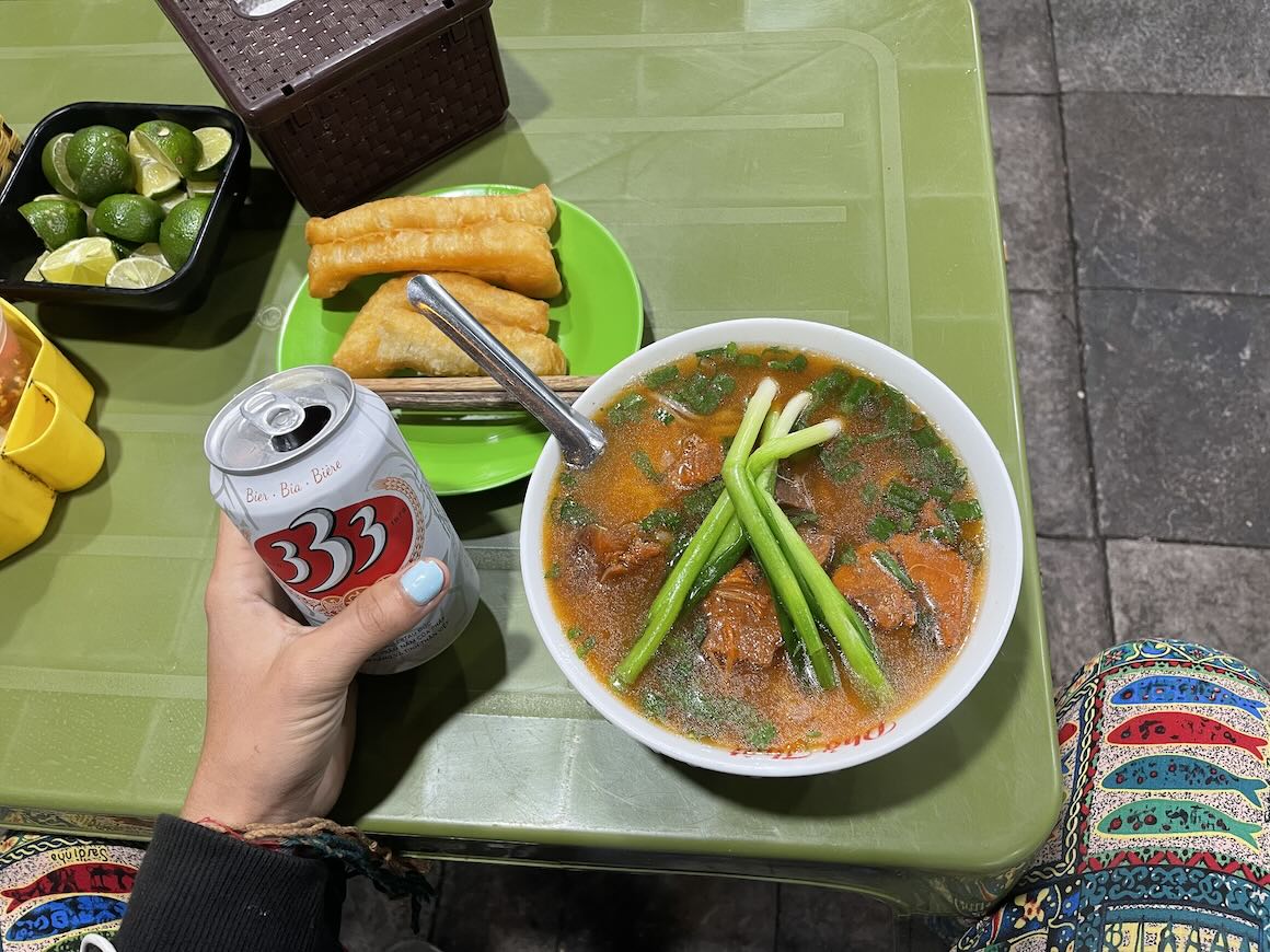 A delicious bowl on pho and a can of beer at a Vietnamese street food stand in Hanoi.