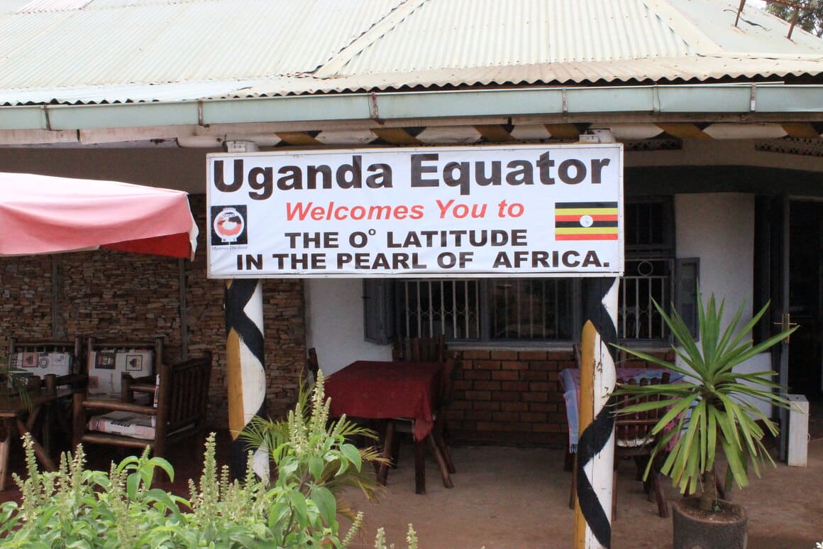 a sign that says uganda equator welcomes you to the 0 lattitude in the pearl of africa hanging from a low roof